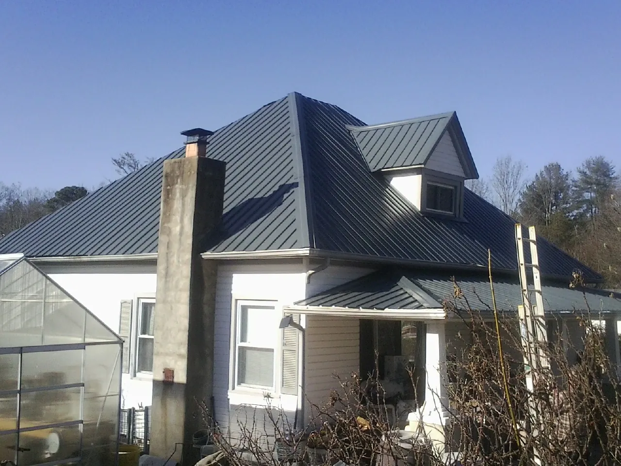 Dark blue standing seam metal roof on a white farmhouse with dormer — Slate & Tile Roof Repair by Roofing Brothers in Lithopolis