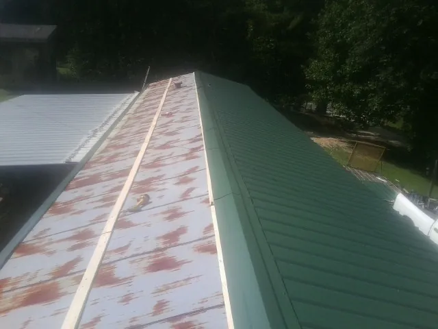 Old rusted panels beside newly installed green metal roofing — Wind Damage Roof Repair by Roofing Brothers in Lithopolis