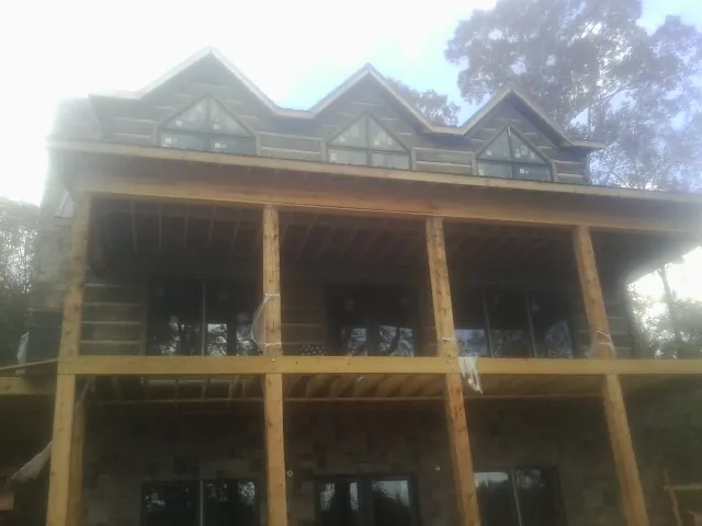 Dormers and porch framing on a large log home under construction — Roof Coating work by our crew in Lithopolis