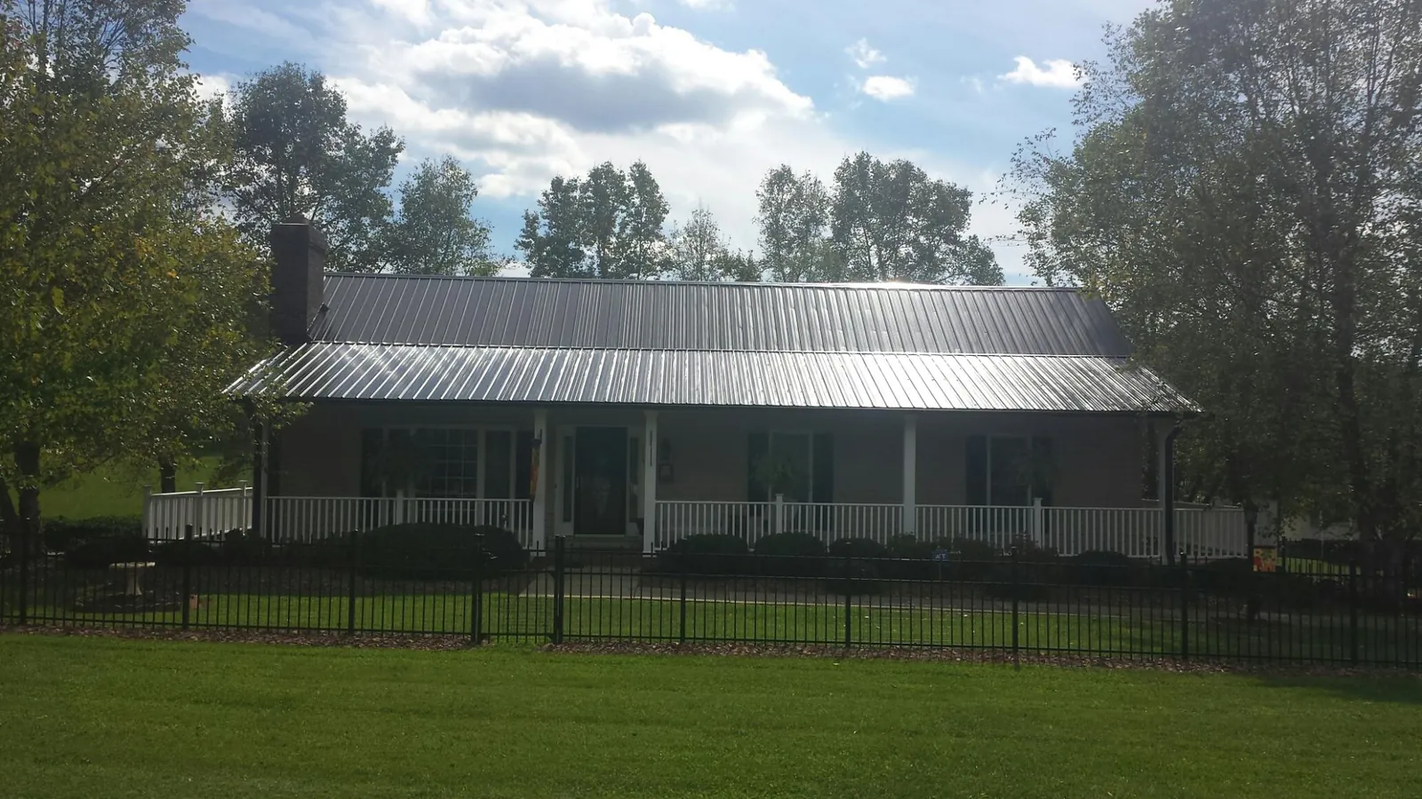 Gray metal roof on a brick ranch with a full width front porch — Gutter Guard Installation work by our crew in Lithopolis